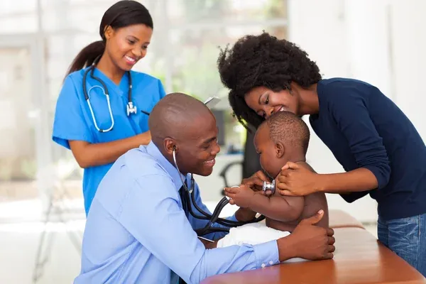 Une infirmière et un médecin du réseau de soins entourent une mère et son bébé